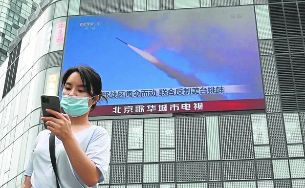 La pantalla gigante de un edificio muestra las maniobras militares de China en el Estrecho de Taiwán. 