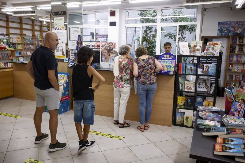 Imagen principal - Arriba, familias haciendo cola para recoger los libros del nuevo curso en la librería. Abajo, a la izquierda, material escolar para este curso. Abajo, a la derecha, Carolina Sánchez, responsable en El Libro Técnico. 