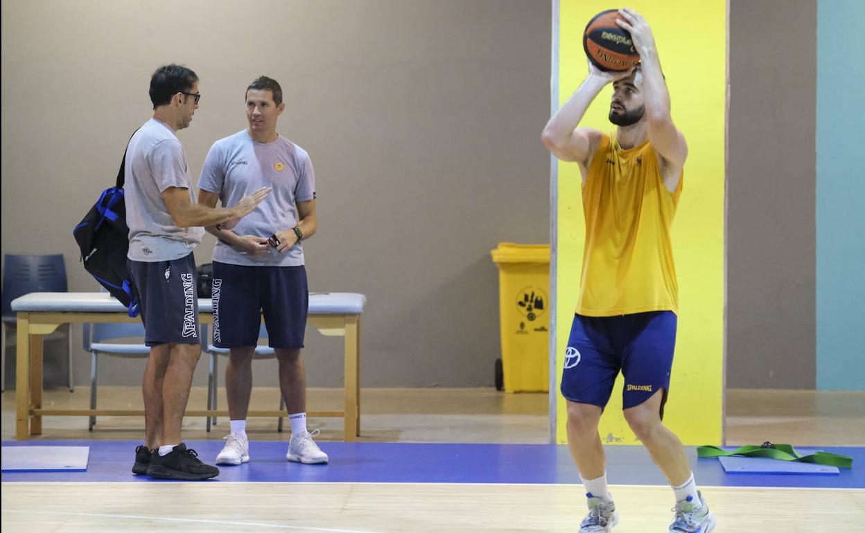 Jovan Kljajic lanza a canasta mientras Willy Villar y Jaka Lakovic conversan tras el entrenamiento en la Sala Club del Gran Canaria Arena. 