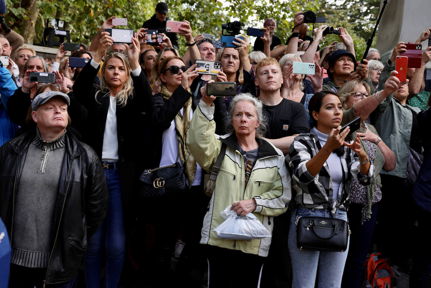 La gente reacciona y toma fotografías cuando el ataúd de la reina Isabel II pasa por The Mall.
