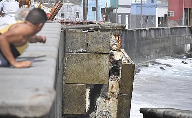 Unos vecinos señalan la parte del muro que se desgajó. 