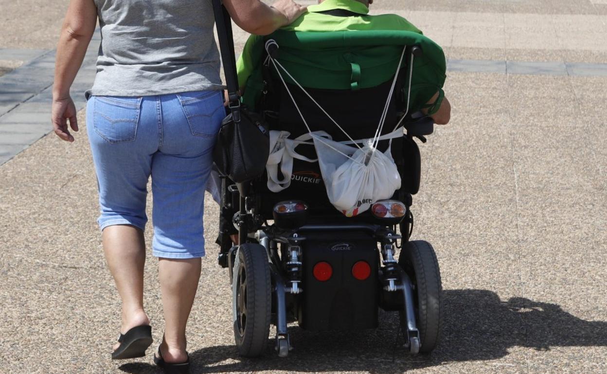 Imagen de archivo de una mujer acompañando a un hombre dependiente. 