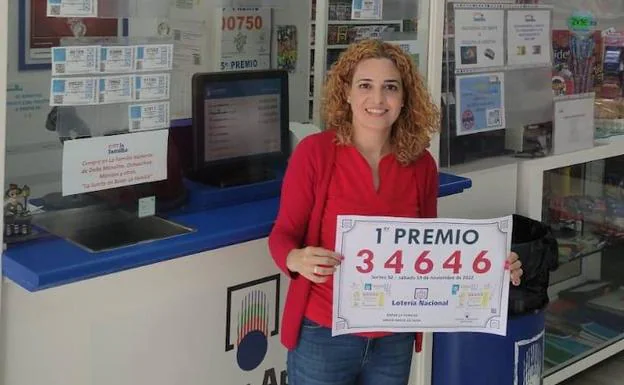 Sherezade Bolaños posa con el cartel que acredita que vendió el número premiado. 