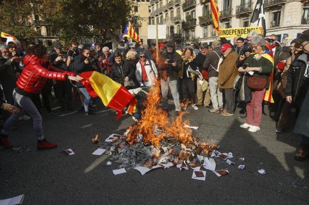 Manifestantes independentistas queman en Barcelona una bandera de España e imágenes de la Constitución.