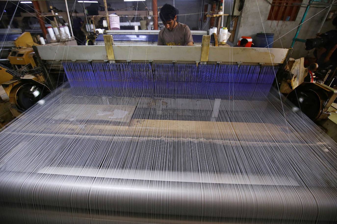 Un hombre trabaja en una fábrica de telares mecánicos en Karachi, Pakistán. La industria textil de Pakistán se ha enfrentado a una importante caída en las exportaciones debido a la disminución del precio en dólares del algodón, que representa el 40 por ciento del costo de la mayoría de las exportaciones textiles, lo que lleva al cierre de miles de telares eléctricos y al desempleo de miles de trabajadores.