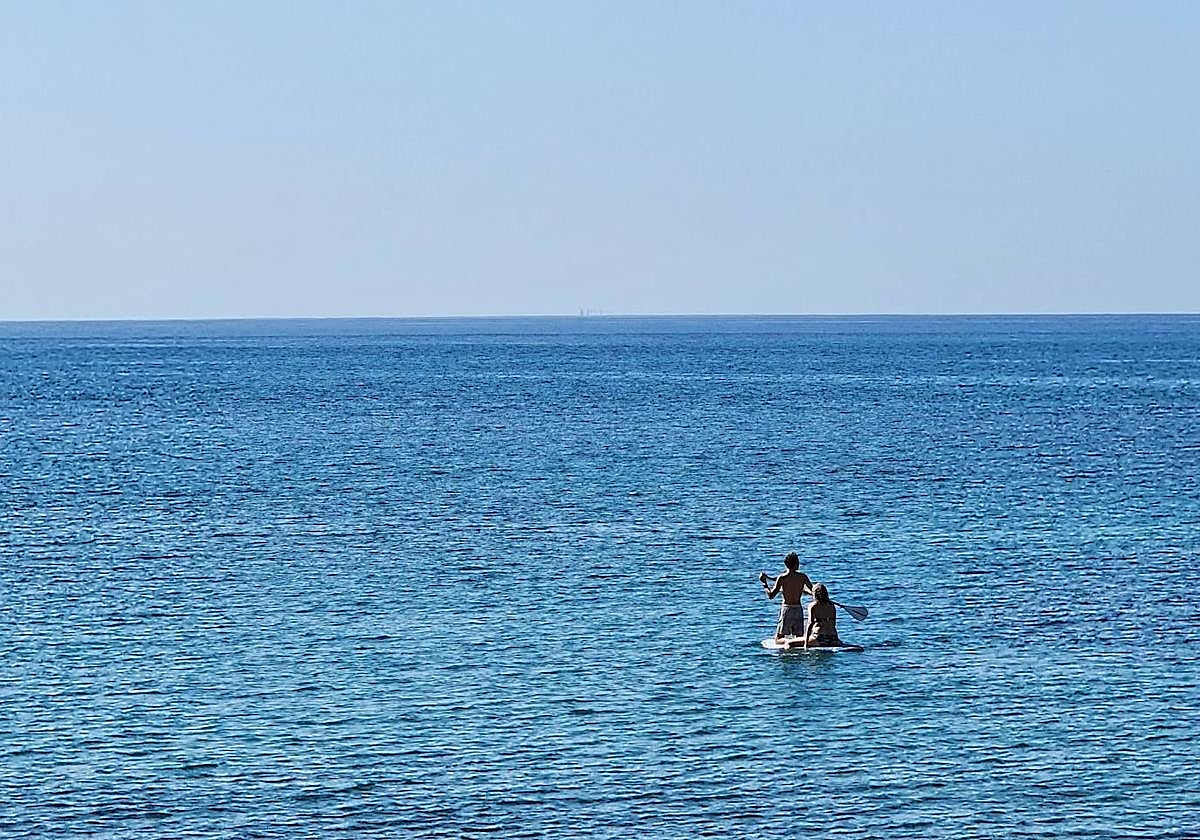 Dos personas navegan sobre una tabla de surf este domingo en Gran Canaria.