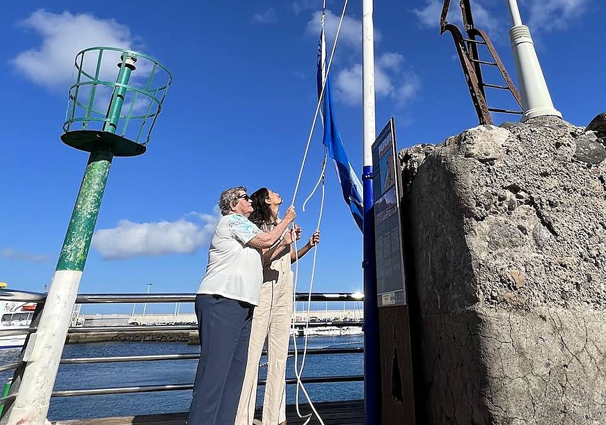 La concejala Sara Perdomo, y la vecina Nieves Ramos izan la bandera azul en Las Nieves.
