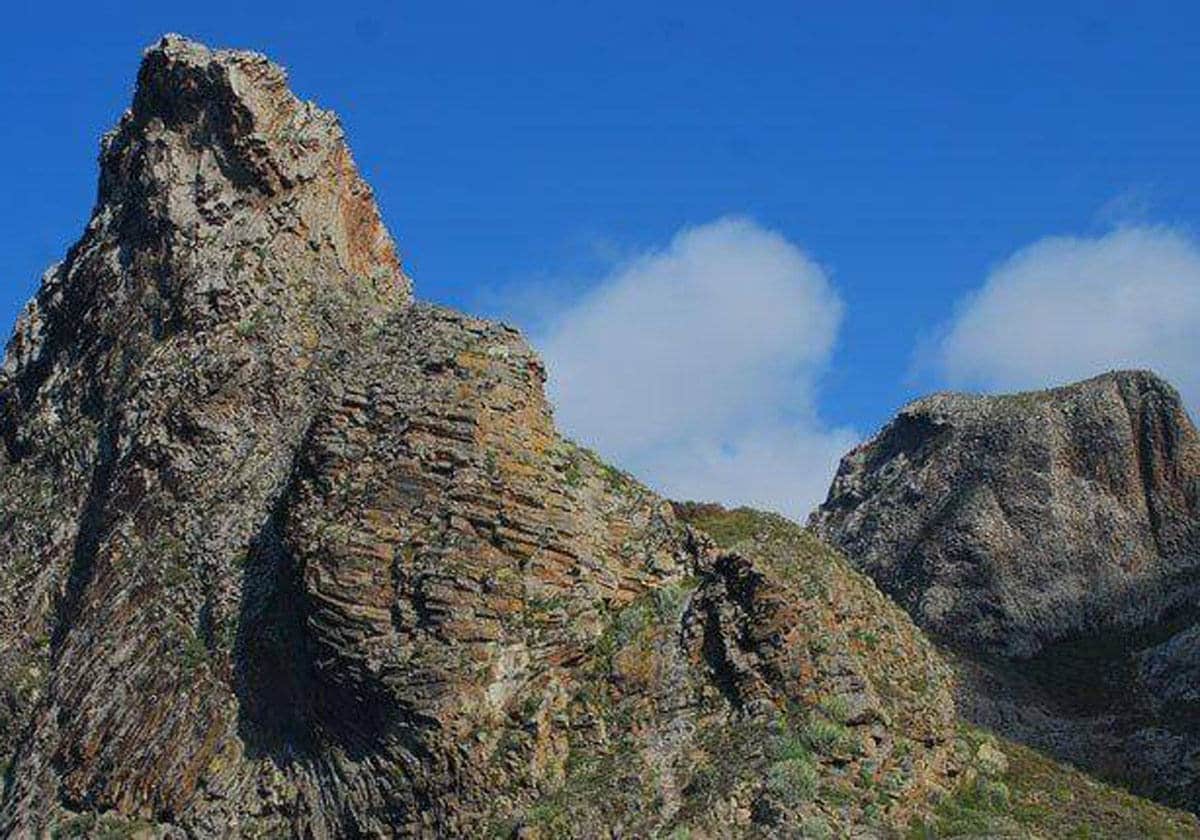 .Las rutas clásicas más largas de Tenerife.- Las rutas de escalada clásica más largas de Tenerife están situadas en el nordeste de la isla, entre las escarpadas montañas y profundos barrancos del Parque Rural de Anaga. Este excepcional espacio natural, de una belleza paisajística abrumadora, alberga bosques húmedos y numerosos roques que aglutinan un centenar de rutas, todas dotadas de un buen equipamiento, con una altura máxima de 250 metros. Algunos itinerarios son aptos para niveles intermedios, pero otros ponen a prueba a los escaladores más experimentados. Uno de los ascensos más conocidos de Anaga es el del roque Negro. Emplazado en el caserío que lleva su nombre, presenta vertientes bien equipadas y con roca de buena calidad. El sector que se conoce como «lado oscuro» –boscoso y con niebla– es ideal para escalar durante las tardes de verano. Otra cima muy popular, y auténtico objeto de deseo para escaladores expertos, es el roque de Las Ánimas, con rutas de bastante dificultad, como algunas de las que aglutina el roque de En Medio.
