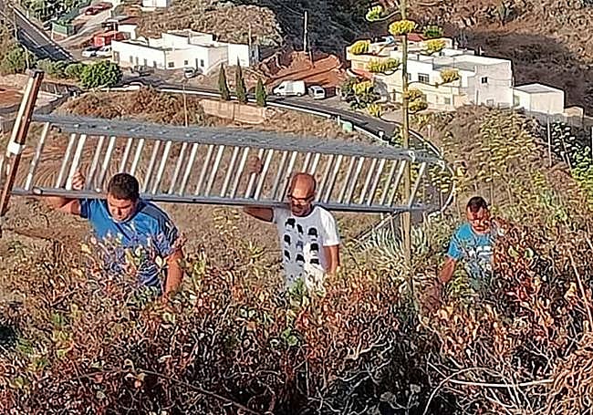 Grupo de colaboradores con la escalera a cuestas en la subida a la montaña para iluminar la cruz anunciadora de las fiestas.