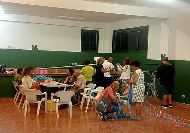 Vecinos de Lomo Magullo, en plena faena confeccionando los adornos que ya están colgados en el pueblo.