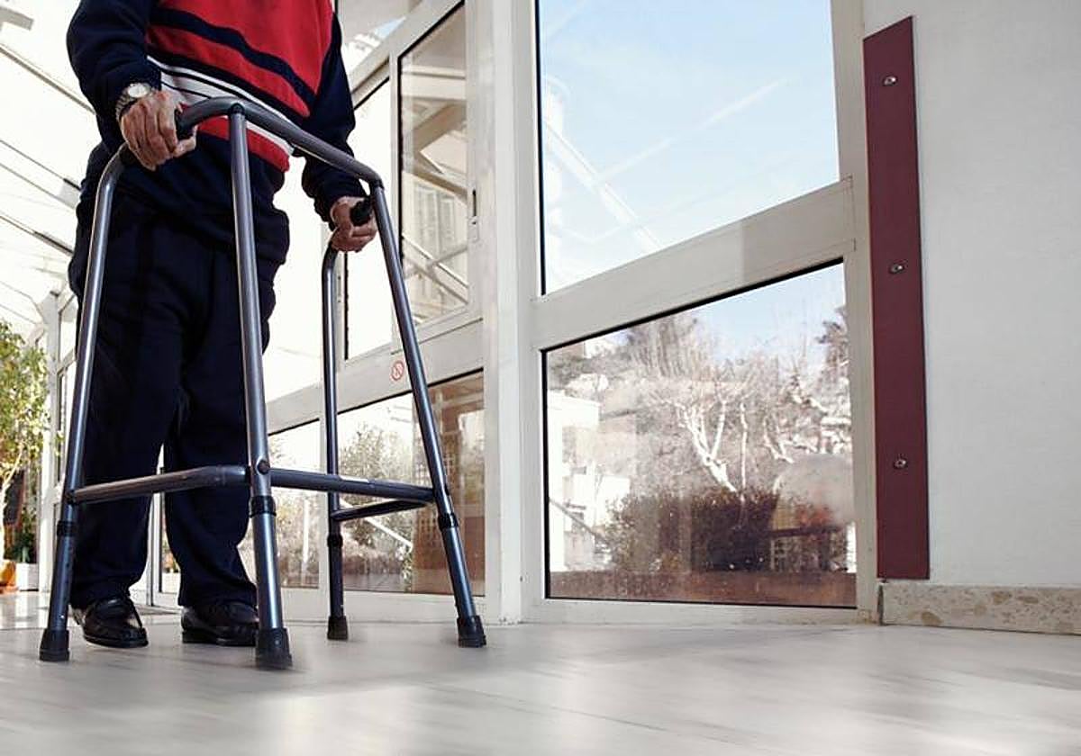 Un mayor dependiente avanza por el pasillo de una residencia.