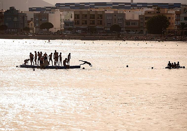 Un grupo de jóvenes se refresca en el mar durante la tarde de este martes en Arinaga.