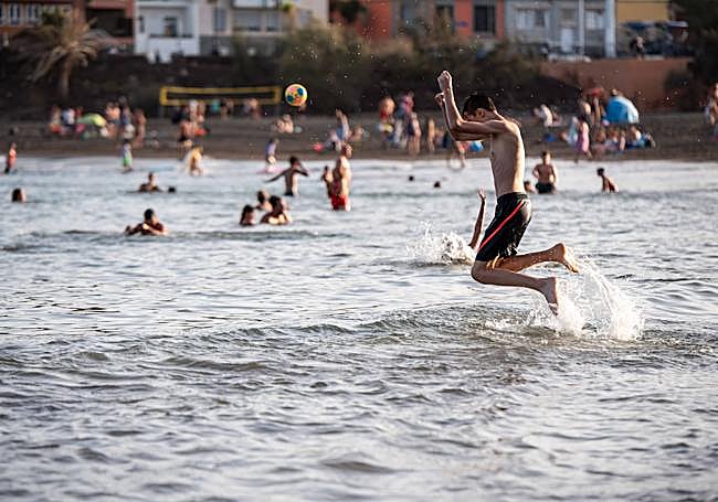 Un joven salta al agua en una playa de Gran Canaria.