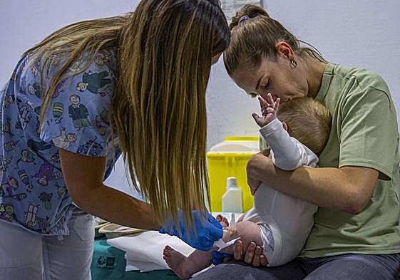 Imagen de archivo de una enfermera pinchando a un bebé.