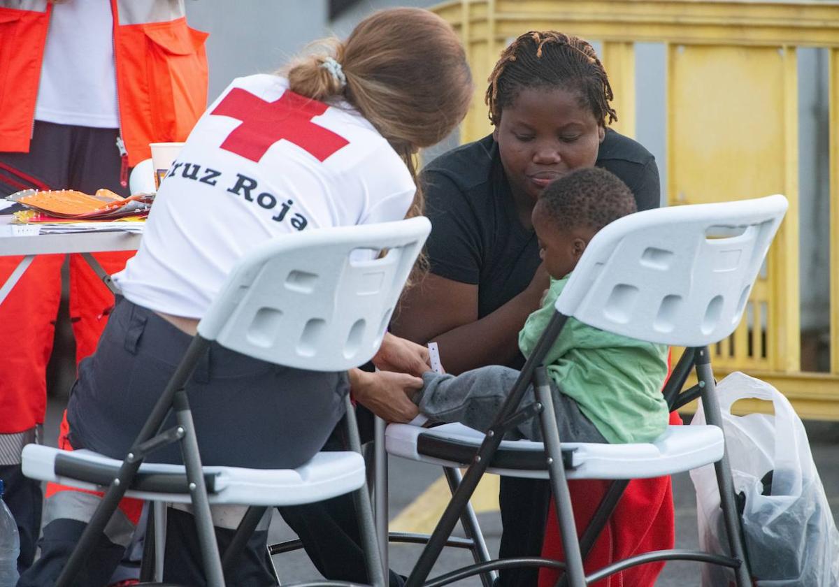 Una voluntaria atiende a su madre y un menor tras llegar a las costas de Canarias.