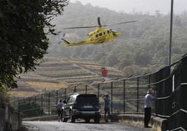 Varios vecinos de El Sauzal observan como un helicóptero que trabaja en las labores de extinción del incendio forestal de Tenerife.