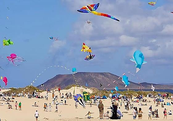 Cometas al vuelo en las dunas de Corralejo con Lobos y, muy al fondo, Lanzarote.