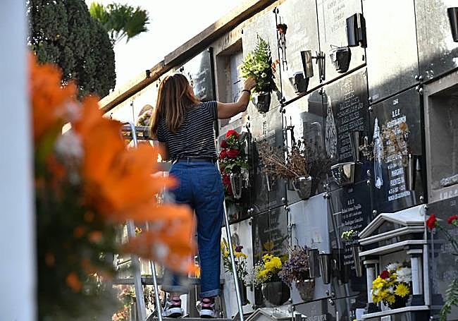 Una ciudadana deposita flores en elnicho de un ser querido.