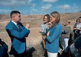 Teodoro Sosa y Sara Aagesen dialogan con el parque eólico de Botija al fondo.