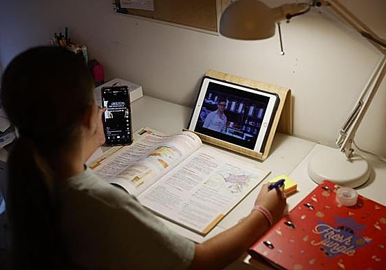 Un menor intenta estudiar con dos dispositivos electrónicos.