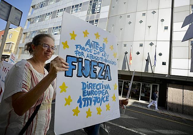 Una profesora de conservatorio frente a la Consejería de Eduación con una pancarta.