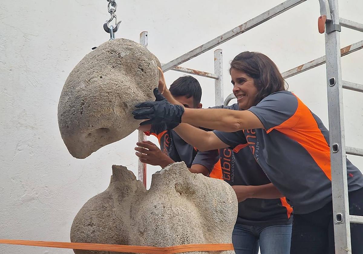 Sara Bosch, ayudada por un tecle grúa pluma, trata de encajar una de las piezas en que se fragmentó la escultura.
