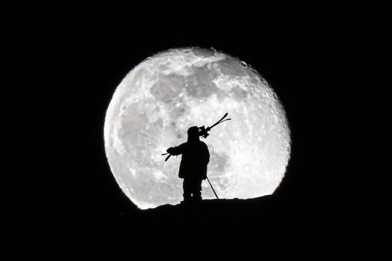 Un esquiador admira la luna desde lo alto de una montaña en una estación de esquí de Gryon, en Suiza. 
