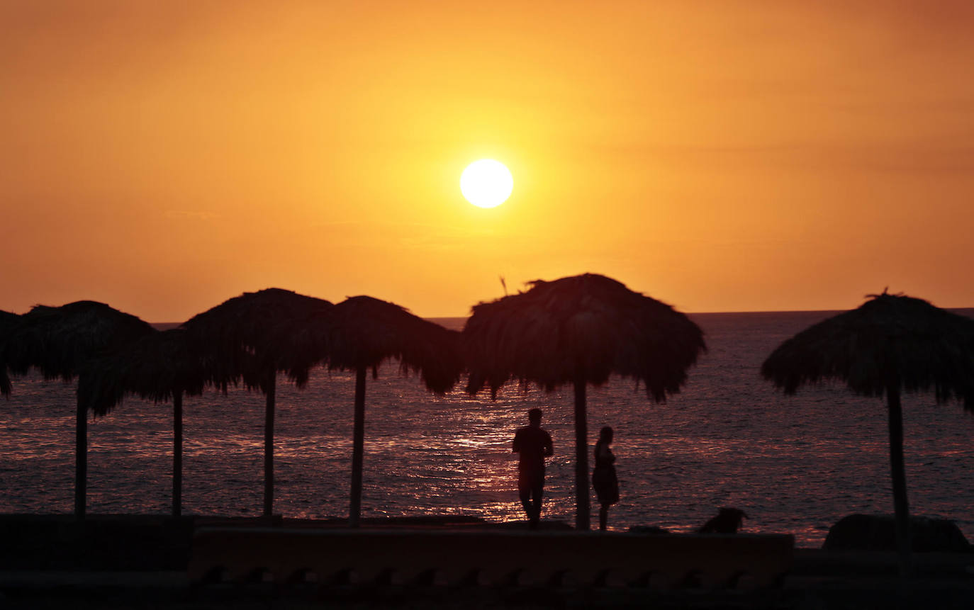 Dos personas caminan frente a una puesta de sol, hoy en La Habana (Cuba). 