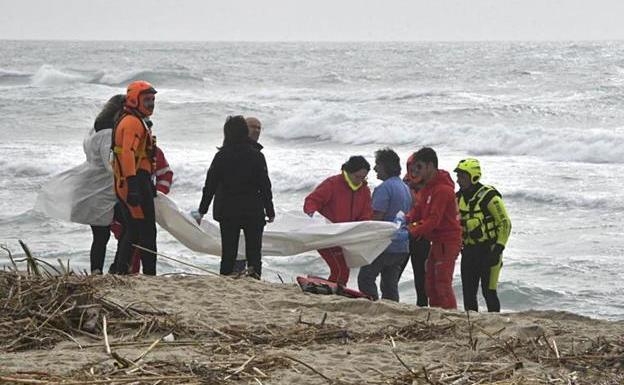 Los equipos de rescate cubren uno de los cadáveres encontrados en la playa de Cutro.