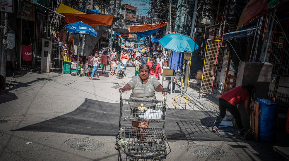Transeúntes caminan por una calle del barrio Mugica, en Buenos Aires (Argentina). No sale en las guías de turismo pero el Barrio Mugica o 'Villa 31', como popularmente se conoce al más emblemático asentamiento de viviendas precarias de Buenos Aires, está impulsando visitas turísticas con un objetivo: mostrar su riqueza cultural y gastronómica y desterrar la imagen de inseguridad y delincuencia que se tiene de lugares como este. 