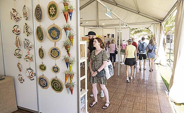 Turistas en los puestos de la Feria de Artesanía de Primavera abierta junto al Faro de Maspalomas. 