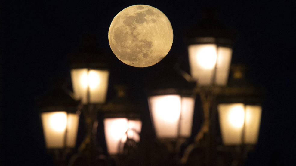 La Luna Llena de Gusano de marzo se eleva sobre la luz de la calle en Skopje, República de Macedonia del Norte. La Luna de Gusano es la última luna llena de la temporada de invierno.