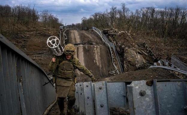 Un soldado ucraniano carga con un lanzamisiles al atravesar uno de los puentes de acceso de Bajmut destruido por los bombardeos rusos.