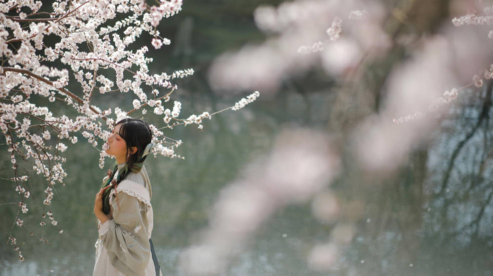 Una mujer posa junto a un melocotonero en flor en Pekín. 