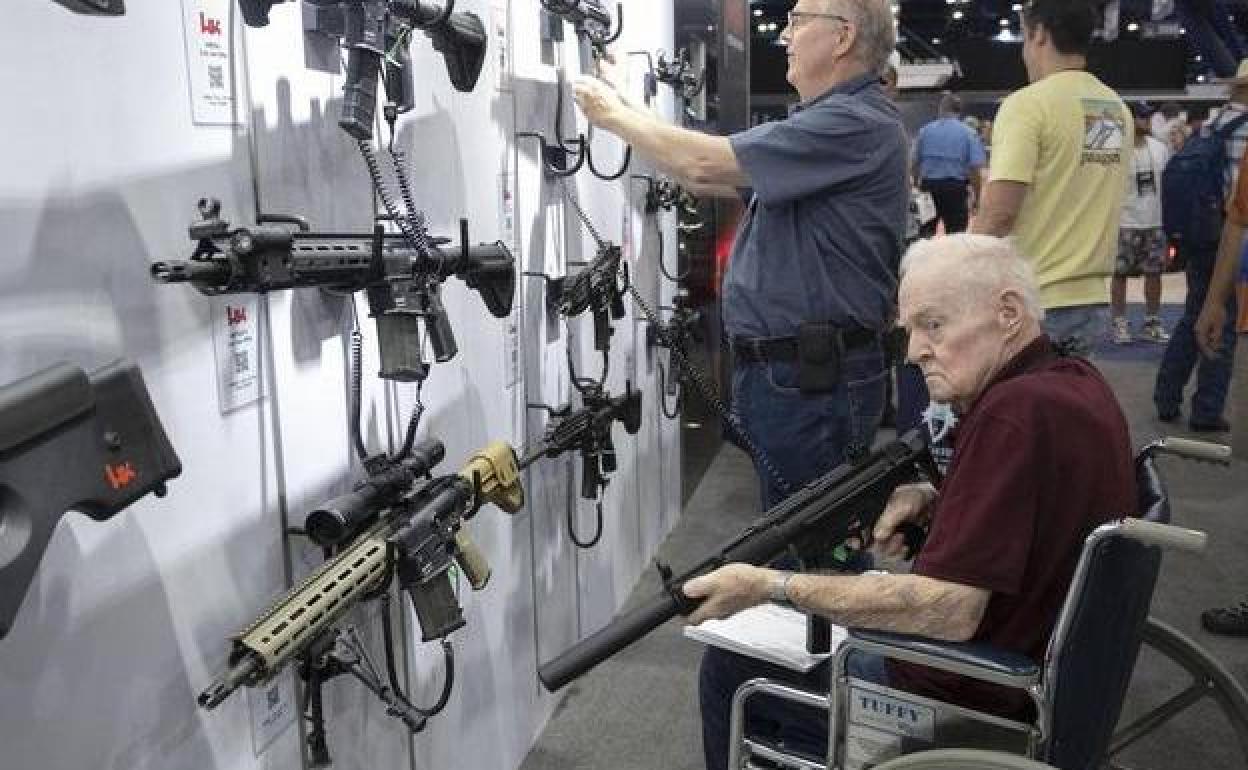 Dos visitantes inspeccionan armas de fuego durante una feria comercial de la Asociación Nacional del Rifle de Estados Unidos