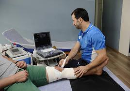 Un fisioterapeuta trata a un deportista lesionado.