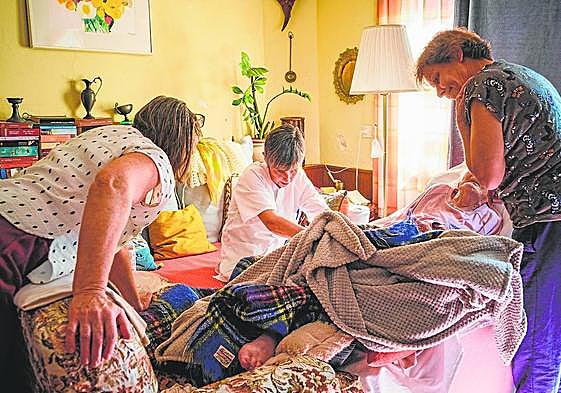 Maisi, en la imagen, atiende a Felizita, de 98 años, mientras habla con su hija Nora ( izq). Conchi (dcha) es como una hija más y ayuda en los ciudados.