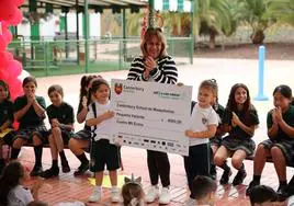Dos alumnas del colegio entregan el cheque con la ayuda a la vicepresidenta de Pequeño Valiente, Montserrat Sánchez.