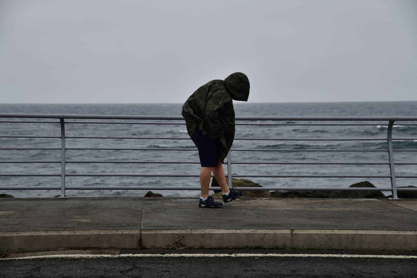 Una persona incumpliendo con las recomendaciones impuestas ante un temporal de lluvia, viendo y fuerte oleaje.