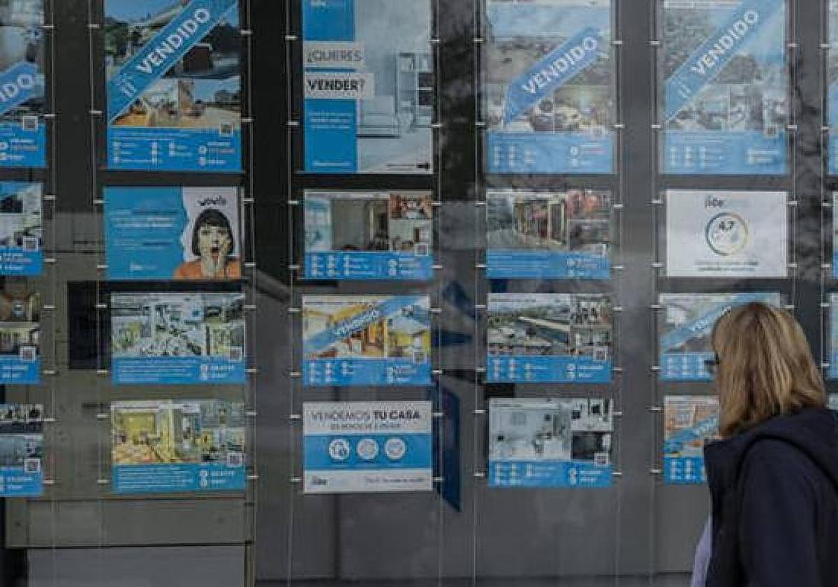 Una mujer mira un escaparate de una inmobiliaria.