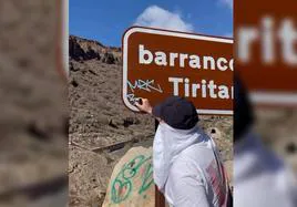 Imagen del hombre pintando en el cartel del barranco de Tiritaña.