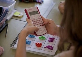 Imagen de archivo de una escolar con una calculadora en clase.