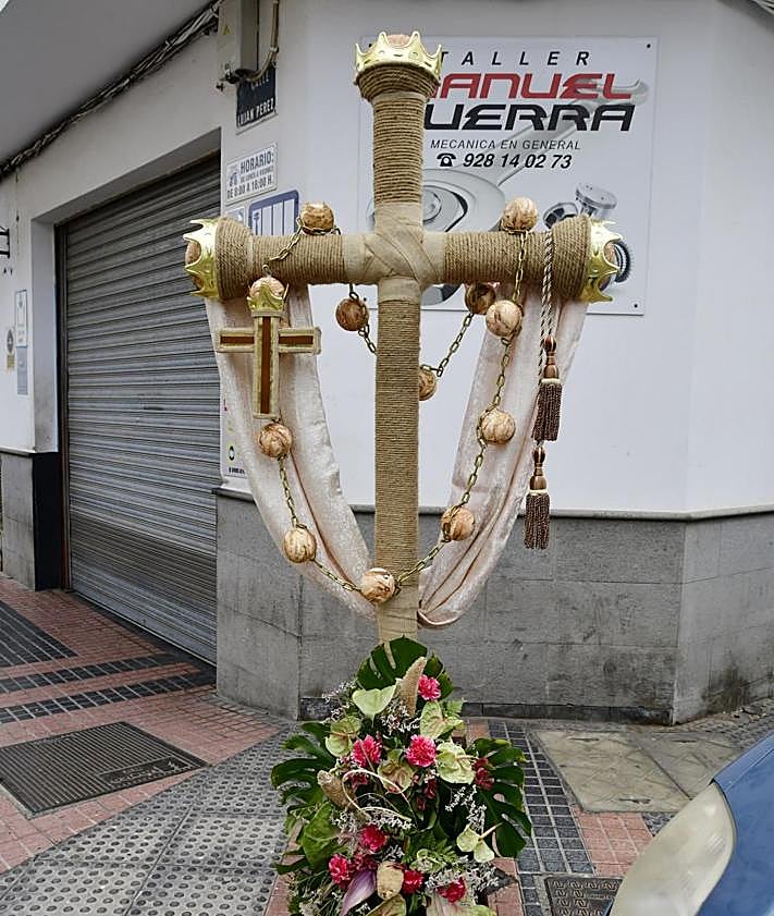 Imagen secundaria 2 - En la foto superior, espectacular mural junto al que pasará la romería. Debajo, una vecina posa con la Vara de la Romera, y una de las cruces engalanadas que estos días luce El Tablero.