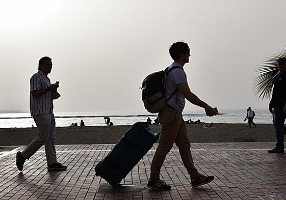 Turistas a su paso por la playa de Maspalomas.