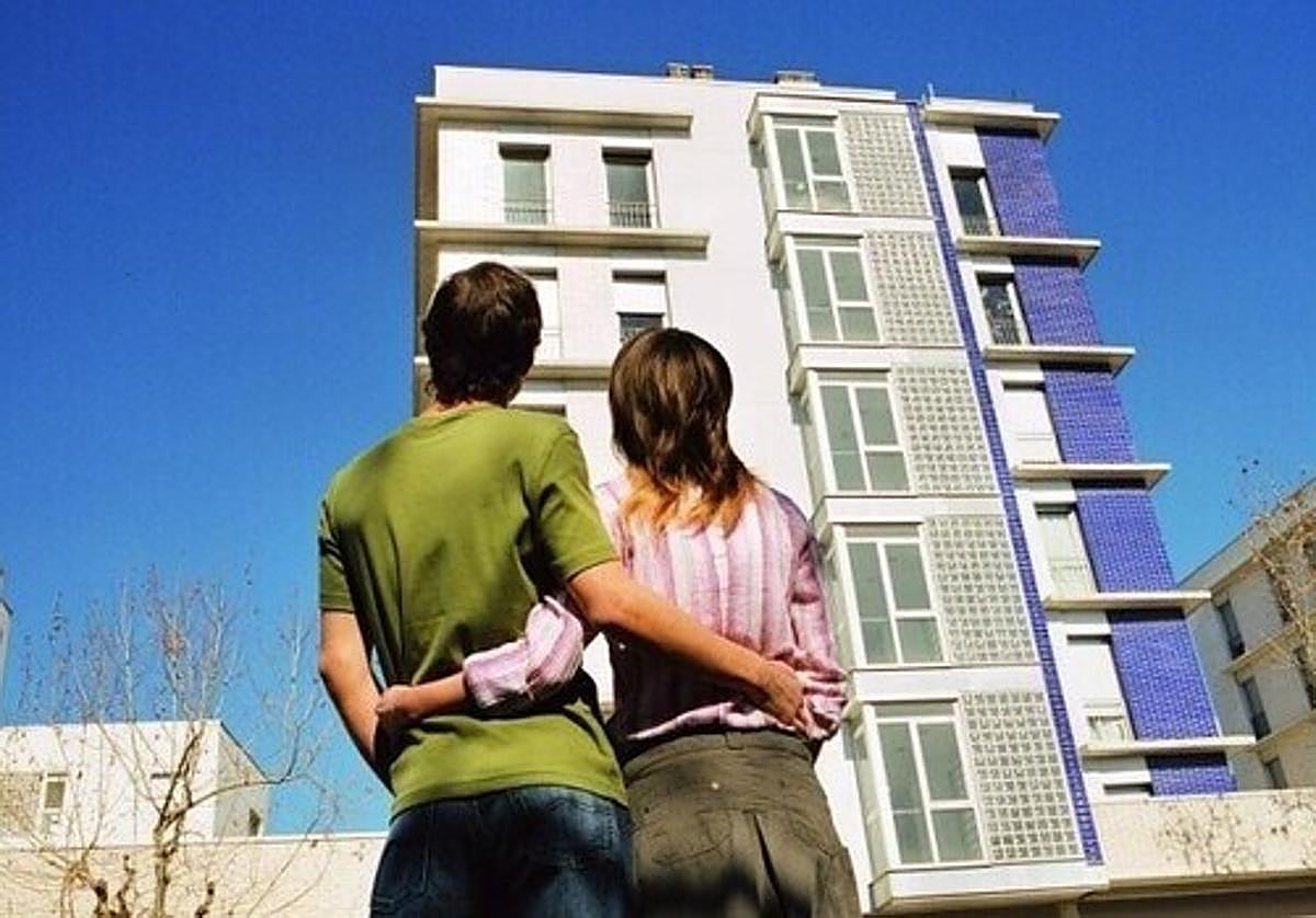 Una pareja contempla un edificio de viviendas.