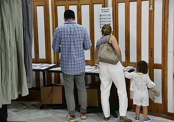 Unos ciudadanos cogen sus papeletas en un colegio electoral de La Isleta este domingo.