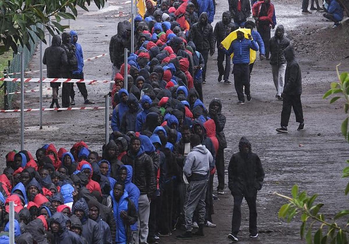 Imagen de archivo de cientos de migrantes de origen subsahariano haciendo fila bajo la lluvia para acceder al centro de acogida para migrantes de Las Raíces en Tenerife.