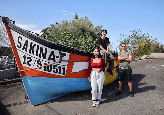 Víktor Arvín, sentado, junto a Zoe Nantón e Hicham Charki posan junto a una patera decorada en el IES Faro de Maspalomas en un proyecto anterior del centro.