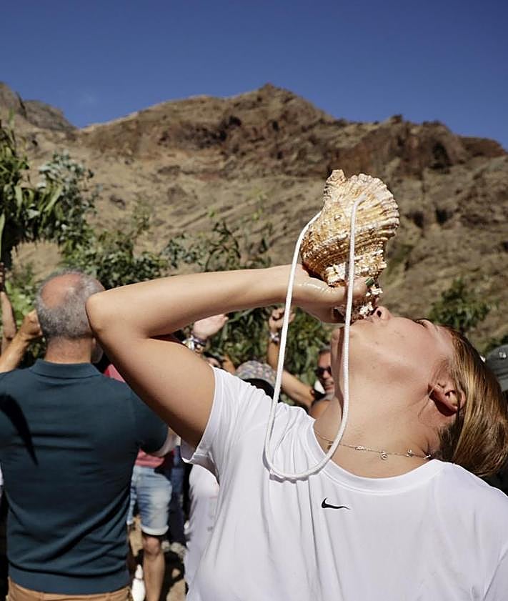 Imagen secundaria 2 - En la foto superior, un romero en mitad de un bosque de ramas. Debajo, la banda Guiniguada, en la Era del Molino, a donde fue a esperar a los romeros, Y al lado, una joven hace sonar un bucio.