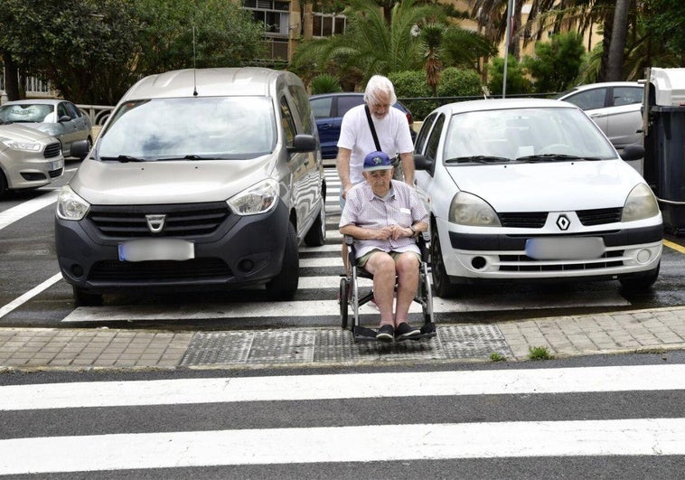 Ángel y Carmelo cruzan por un paso de peatones ocupado por dos coches.